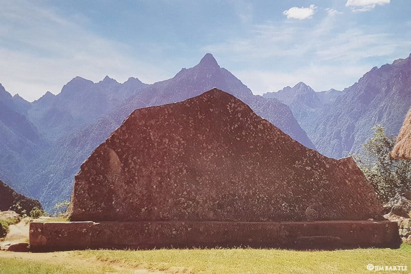 Roca Sagrada de Machu Picchu alineada con montaña Yanantin al fondo, ejemplo de arquitectura inca en armonía con paisaje andino, fotografía de Jim Bartle