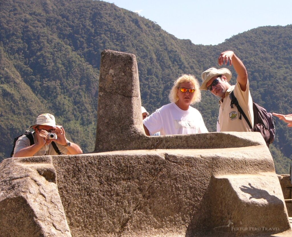 Turistas fotografiando el Intihuatana o Poste de Amarre del Sol en Machu Picchu, reloj solar sagrado inca actualmente restringido para preservación del patrimonio arqueológico peruano